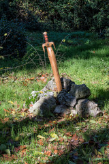 Espada de Excalibur/ una espada de madera clavada en una piedra decorando un jardín en Madrid. España.