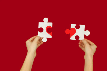 puzzle with a red heart in the hands of a loving couple. valentine's day concept.on a isolated backg