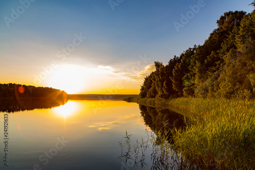 Fotografie, Obraz ein See umgeben von Wald bei Sonnenuntergang