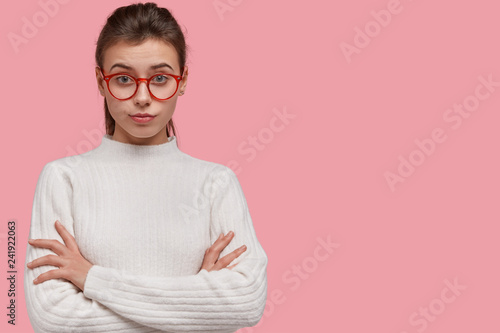 Fotografía Studio shot of pretty woman looks with attentive facial expression, keeps hands