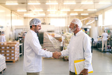 Two Happy Coworkers Shaking Hands While Standing In The Food Factory.