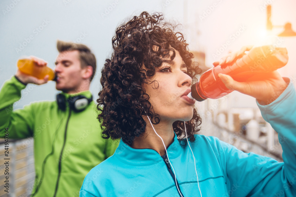 Sporty runners couple drinking energy drink  - obrazy, fototapety, plakaty 