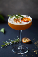 Christmas cocktail of amaretto sour with dehydrated clementine and rosemary