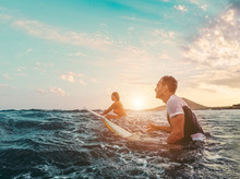 Fit Couple Surfing At Sunset