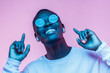 Young smiling african american man listening to music with earphones, dancing isolated on pink background