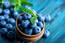 Bowl Of Fresh Blueberries On Blue Rustic Wooden Table Closeup.