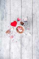 Girl hands hold little heart shaped gift box, old wooden table with hot chocolate with marshmallow hearts and tulip flowers, Valentine day background copy space top view, hands in picture flatlay