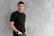 © Damir Khabirov - Horizontal portrait of young man standing isolated against gray textured wall feeling confident and looking optimistic in casual clothes, copyspace for advertising your goods or services