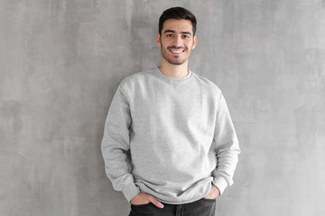 Wall Mural - Young man in oversized sweatshirt isolated on textured gray wall background