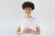 © Damir Khabirov - Portrait of beautiful young woman holding smart phone, looking at camera, isolated on gray background