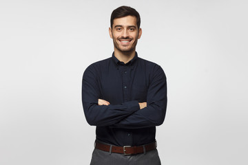 modern businessman in deep blue shirt standing with crossed arms, isolated on gray background