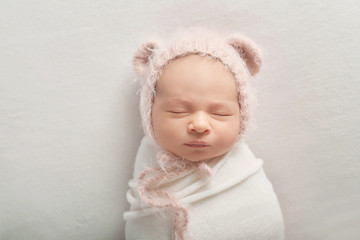 Cute newborn baby lies swaddled in a white blanket. Baby goods packaging template. Closeup portrait of newborn baby with smile on face. Healthy and medical concept. 