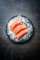 Wall Mural - Portioned raw salmon fillets in ice on plate - Top of view