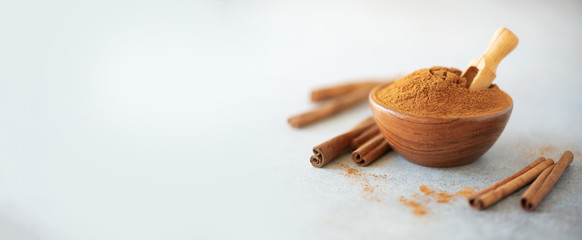 Wall Mural - Cinnamon sticks and powder on grey background. Spices for ayurvedic treatment. Alternative medicine concept