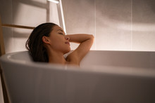 Luxury Bath Woman Relaxing In Hotel Spa Bathtub Or Home Bathroom For Total Relaxation. Asian Lady Taking A Bath Sleeping In Warm Water, Winter Wellness.