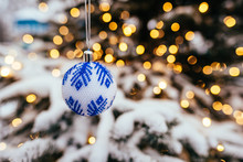 Blue White Christmas Ball On Fir Tree Branch Close Up Golden Yellow Light Bokeh Background
