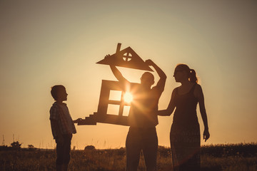 Happy family standing on the field at the sunset time.