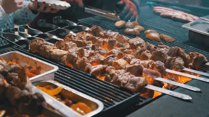 Wall Mural - Meat Grilled on Skewers on the Grill on the Street Market. Tasty grilled food. Pork meat prepared on fire. Street food. Barbecue party. Roasted meat with crust.