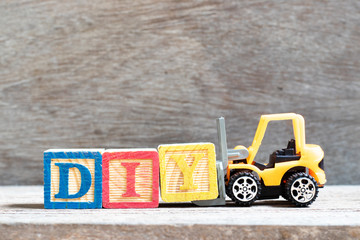 Sticker - Toy forklift hold letter block Y to complete word  DIY (abbreviation of do it yourself) on wood background