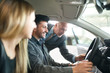 © Minerva Studio - Happy young family talking to the salesman and choosing their new car in a showroom