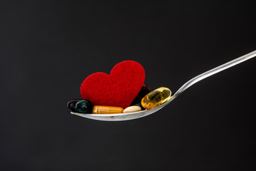 Wall Mural - the colorful medical supplement and drug pills with red heart in spoon , pharmaceutical cardiology drugs for heart health care disease concept