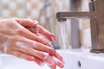  Hand hygiene. Person in the bathroom is cleaning and washing hands using soap foam