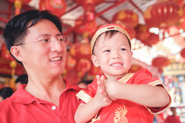 asian family celebrating chinese new year, cute little 2 years old toddler boy child in traditional 