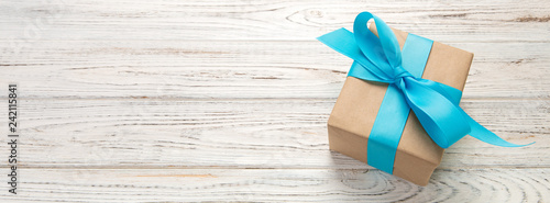 Fotografía Beautiful gift box with a blue bow on the white wooden table