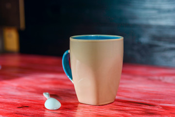 A mug of fresh coffee, on a red wooden background.