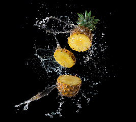 Wall Mural - slice of yellow pineapple with water splashing isolated on black background