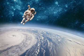 Wall Mural - Astronaut in outer space against the backdrop of the planet earth. Typhoon over planet Earth.