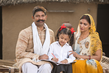 Wall Mural - Rural parents helping daughter to do school homework