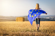 Woman running with waving european union flag in countryside