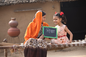 Wall Mural - Mother with her daughter holding slate at village