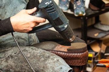 close up of the hands of a man repairing shoes