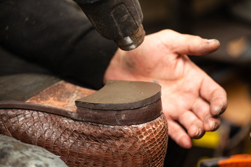 close up of the hands of a man repairing shoes