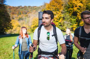 Wall Mural - smiling man trekking with friends in the nature, hikers exploring places