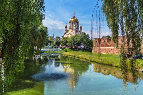 Foto Nice scenario with a tall church and a lake with trees around in Romania