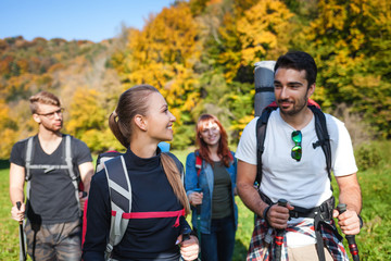 Wall Mural - group of smiling friends trekking together in the nature, hikers exploring places