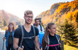 © leszekglasner - Authentic group of friends on tourist trip walking with backpacks and trekking sticks