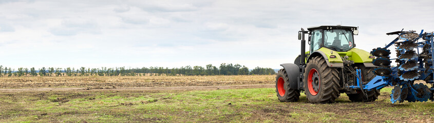 Poster - Tractor working in a field against a cloudy sky
