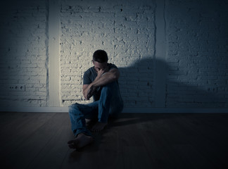 Desperate lonely caucasian man suffering from depression sitting alone on floor at home