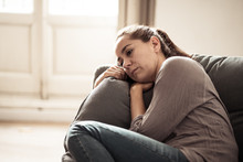 Young Woman Suffering From Depression Feeling Sad And Lonely On Sofa At Home