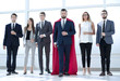 © ASDF - businessman in a red superhero cloak and his business team