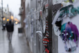 Fototapeta  - Ulica w zimowe popołudnie z obdrapanym murem pełnym plakatów