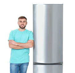 Wall Mural - Young man near closed refrigerator on white background