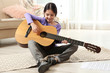 © New Africa - Cute little girl playing guitar on floor in room