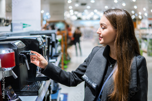 Fotografía Smart modern female customer choosing coffee machine at electronics store