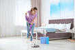 © New Africa - Young woman washing floor with mop in bedroom. Cleaning service