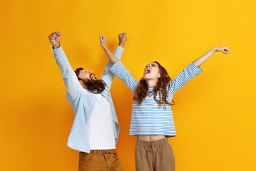 Wall Mural - young happy couple won emotionally celebrating win on colored yellow background